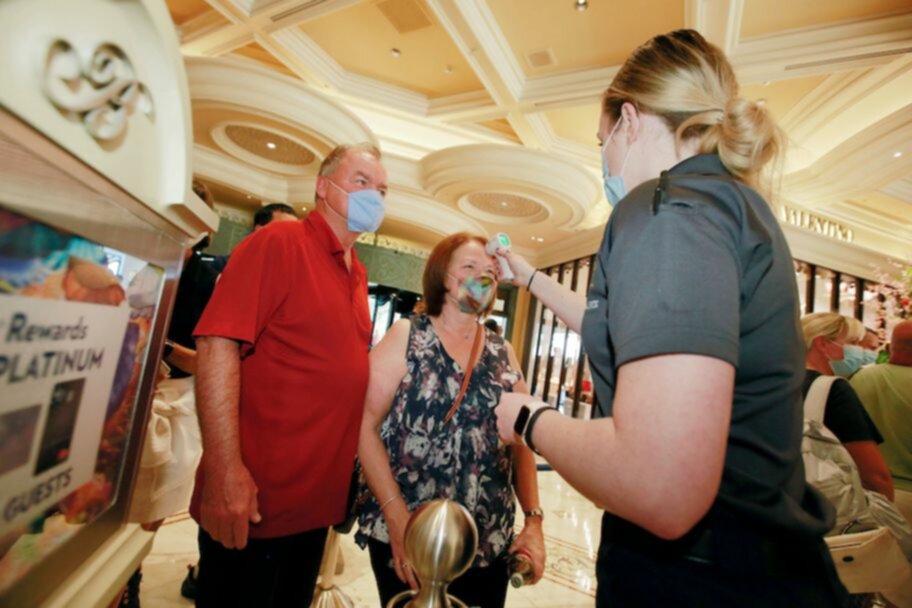 bellagio casino staffer takes guests temperatures as las vegas casinos reopen