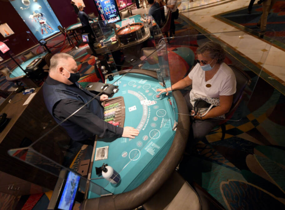 las vegas casino dealer and gambler wear face masks as they gamble in reopened las vegas casinos