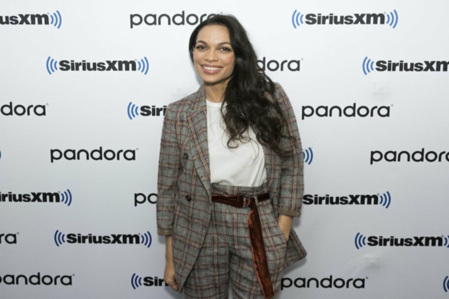 rosario dawson in plaid suit in front of siriusxm pandora step and repeat