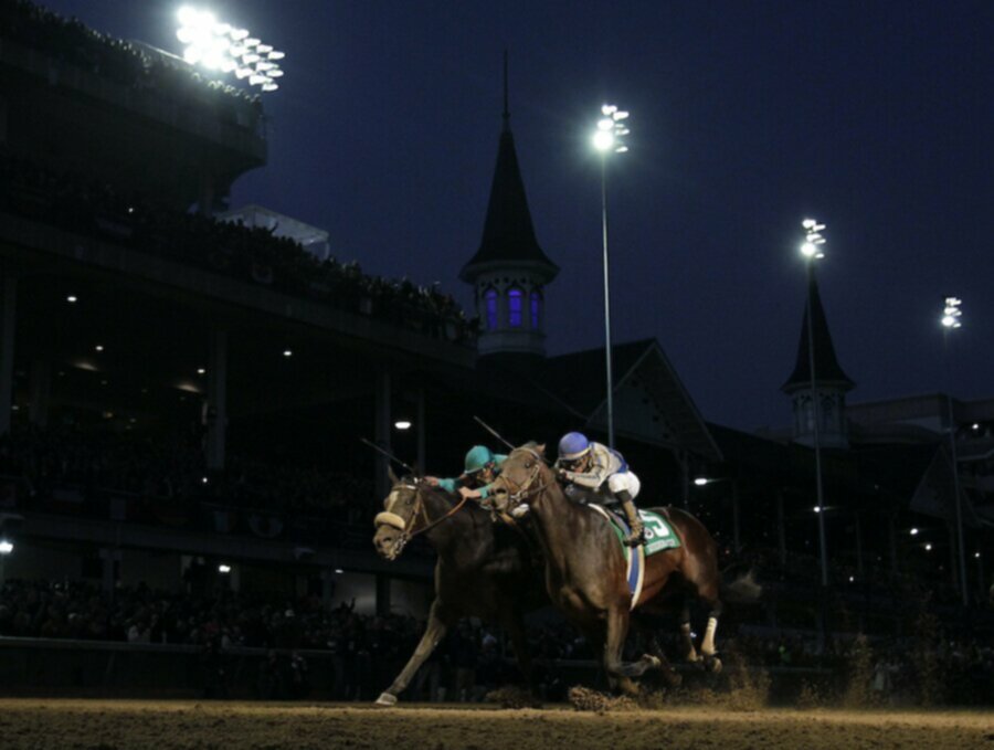 horses and jockeys at night at churchill downs during breeders cup