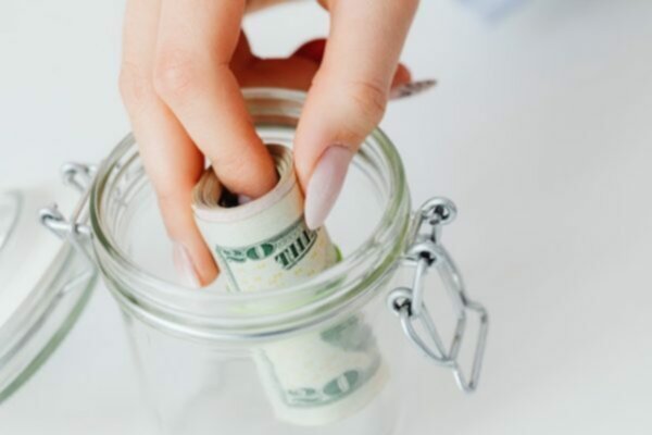 person taking roll of 20 dollar bills from a jar